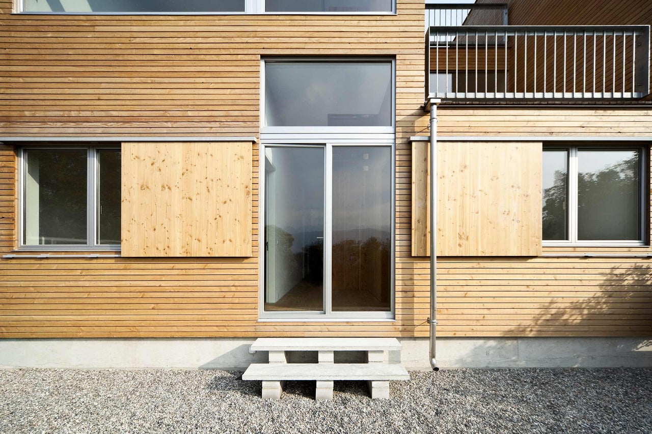 Hausfassade mit Holzverkleidung, Fenster und Schiebetüren