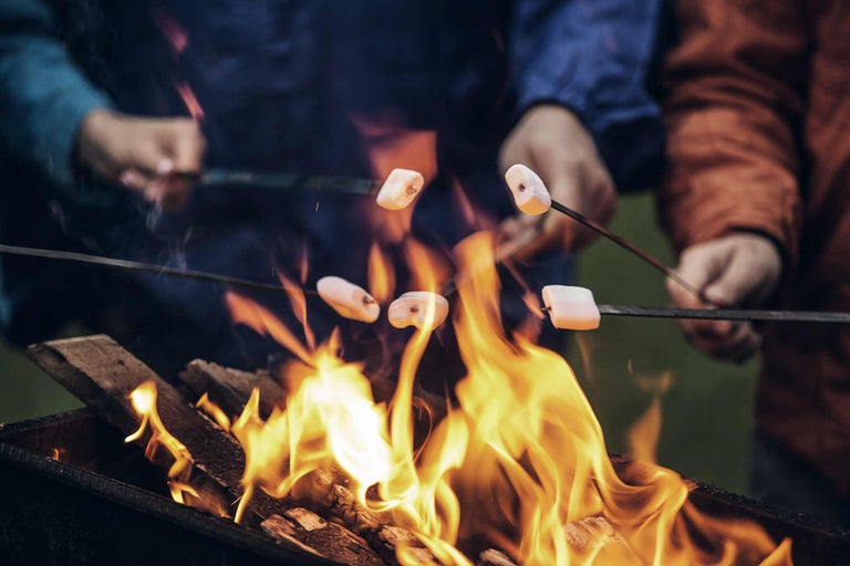 Marshmallows werden über einem Lagerfeuer geröstet.