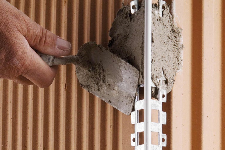 Auftragen von Mörtel an einer Wand mit einer Maurerkelle zur Installation einer Rohrschelle.