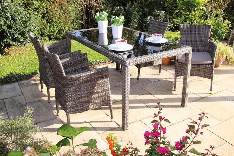Gartentisch mit Glasplatte und vier Rattansesseln auf einer Terrasse