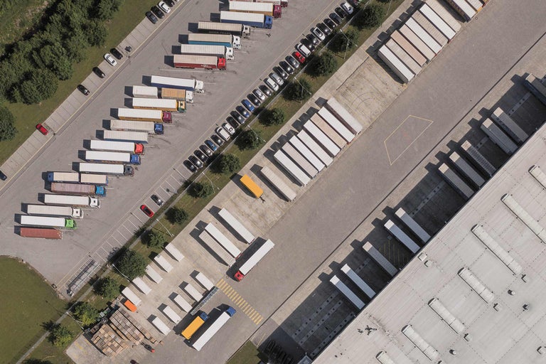 Luftaufnahme von einem Lager mit geparkten Lastwagen und Autos
