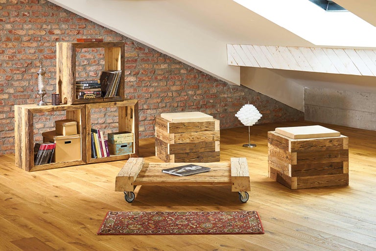 Wohnzimmer mit Regal, Tisch, Hockern, Teppich und Lampe im Dachgeschoss