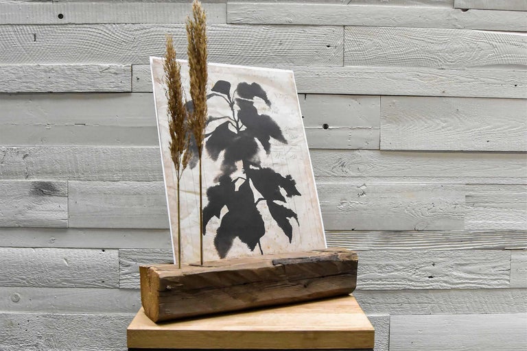 Dekoration mit Blattmotiv auf Holzsockel und Gräsern