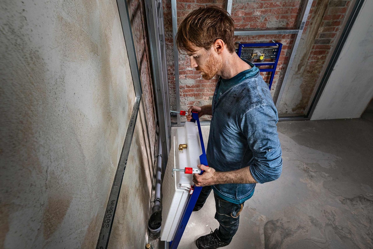 Installateur montiert Vorwandelement im Badezimmer.