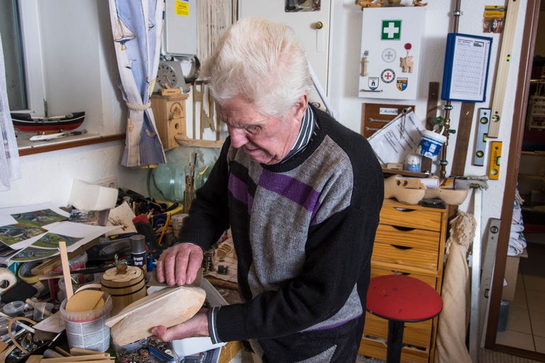 Mann schleift Holzstück in Werkstatt mit Werkzeugen und Zubehör