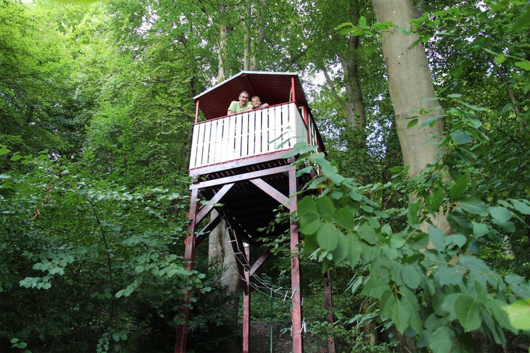 Ein Baumhaus aus Holz mit Personen im Wald