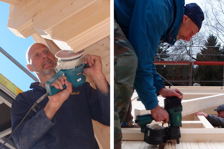 Zwei Männer arbeiten an einer Holzkonstruktion, einer mit einem Schleifgerät, der andere mit einem Druckluftnagler.