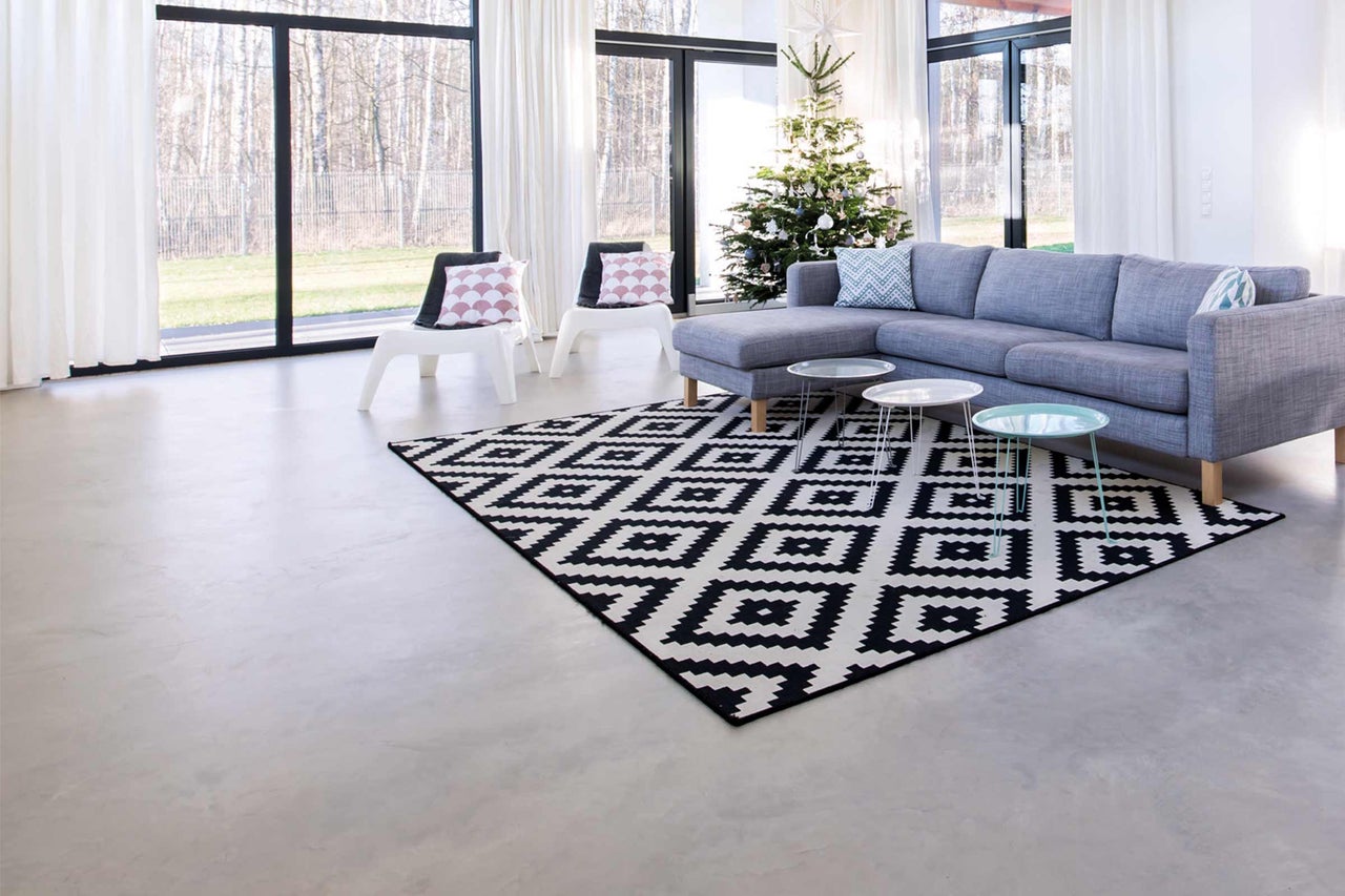 Wohnzimmer mit grauer Couch, gemustertem Teppich und Weihnachtsbaum