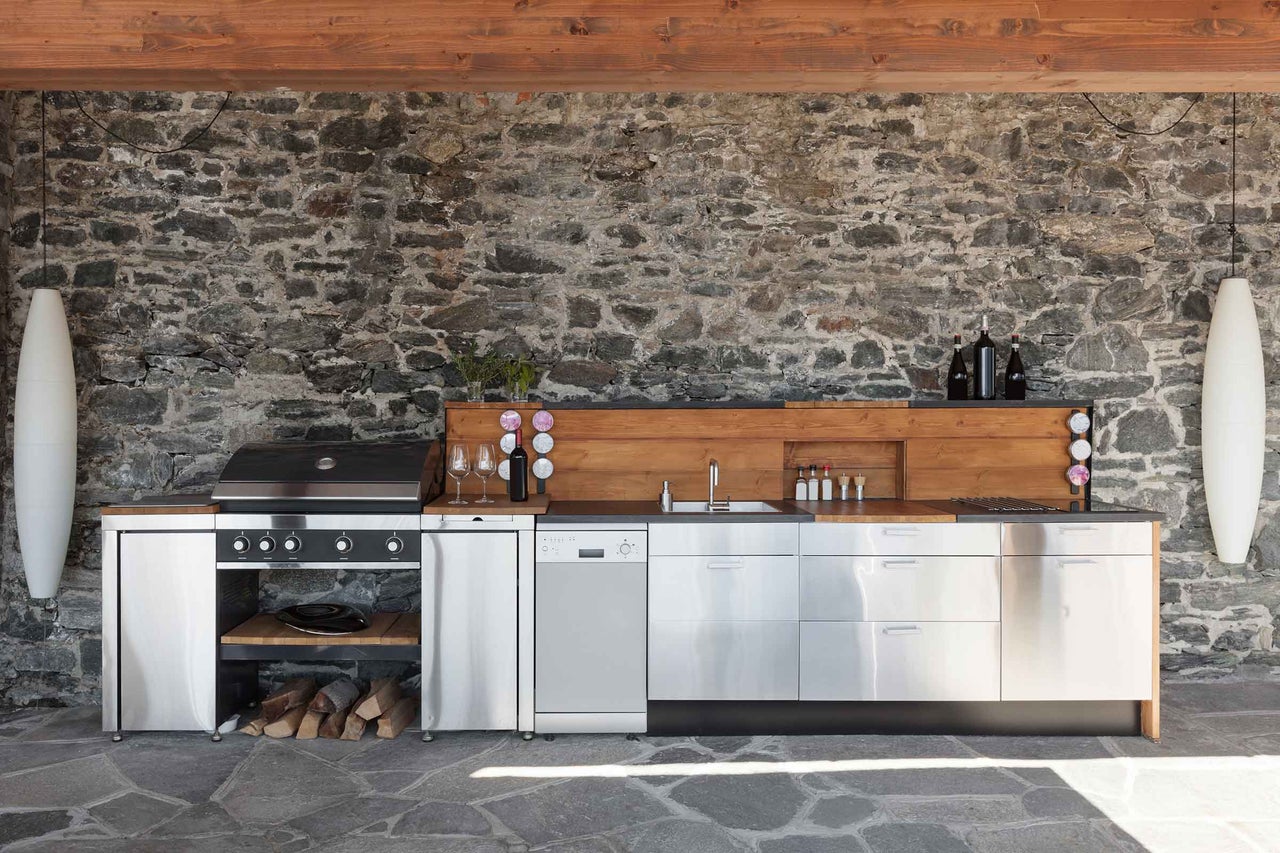 Außenküche mit Grill, Spüle, Arbeitsflächen und Steinwand