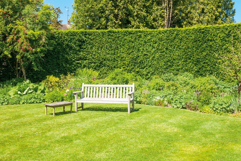 Garten mit Rasenfläche, Hecke, Gartenbank und kleinem Tisch