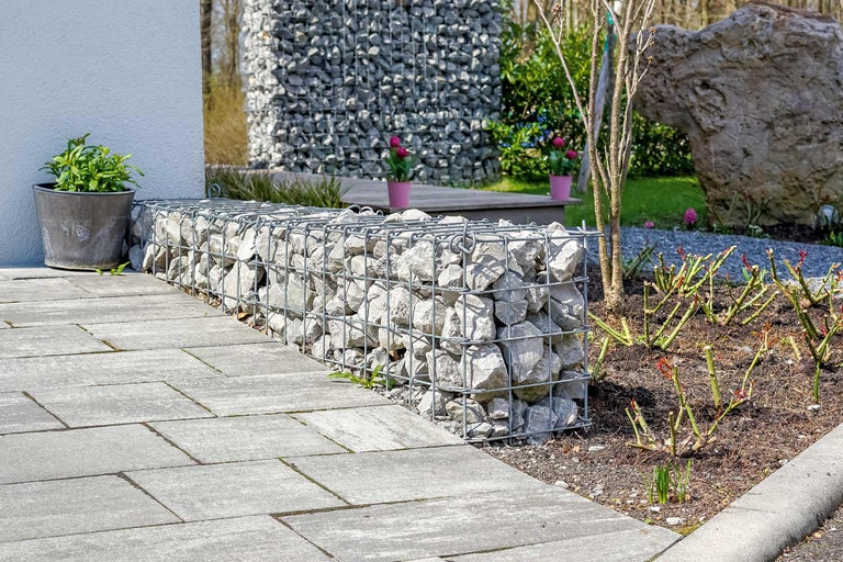 Außenbereich mit Gabionenbank, Steinpflaster und Pflanze in einem Topf