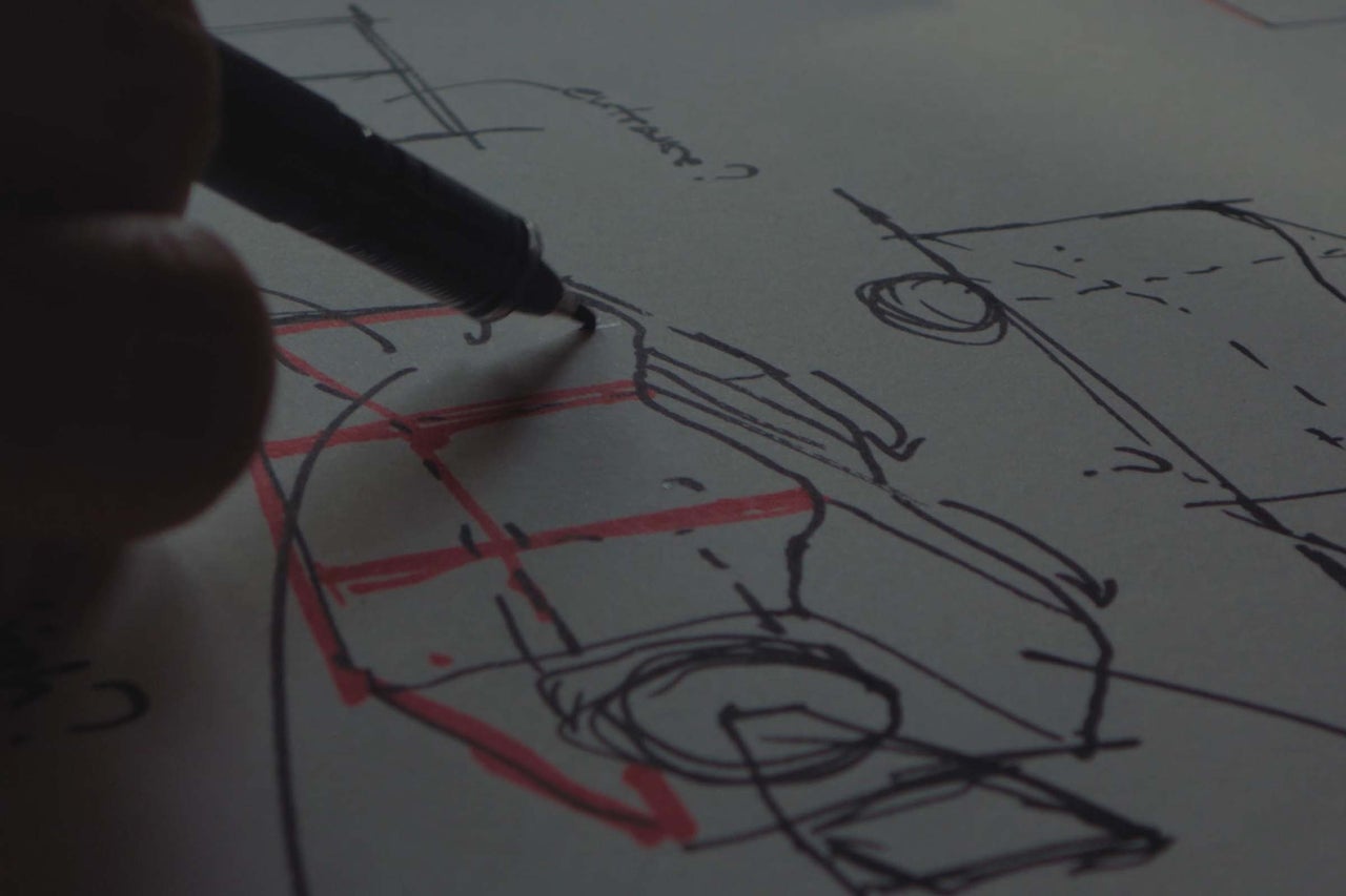 Hand beim Zeichnen einer technischen Skizze mit einem Stift auf Papier