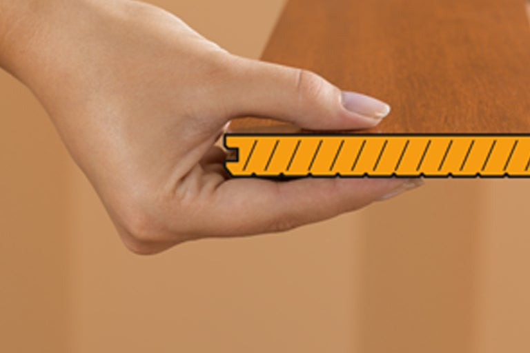 Eine Hand hält eine Laminatdiele, die die Verbindungstechnik zeigt.