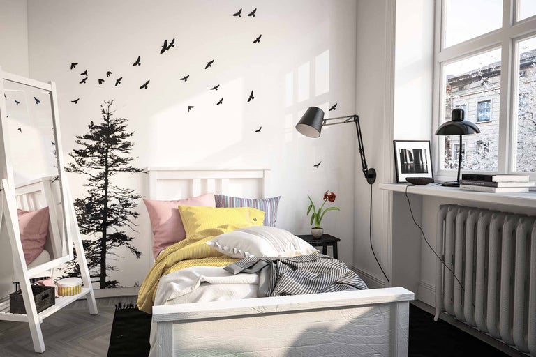 Schlafzimmer mit Bett, Nachttisch, Lampe und Wanddekorationen mit Vogel- und Baummotiven