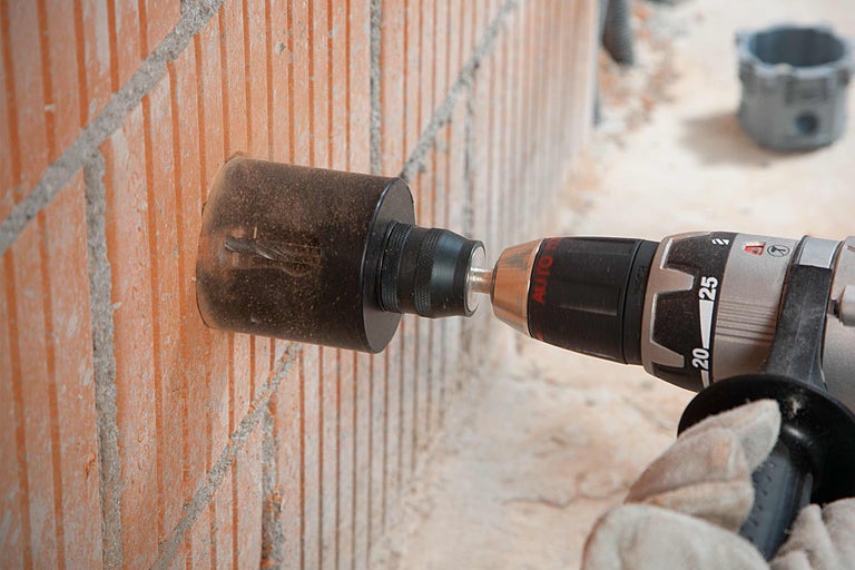 Eine Bohrmaschine bohrt ein Loch in eine Ziegelwand.