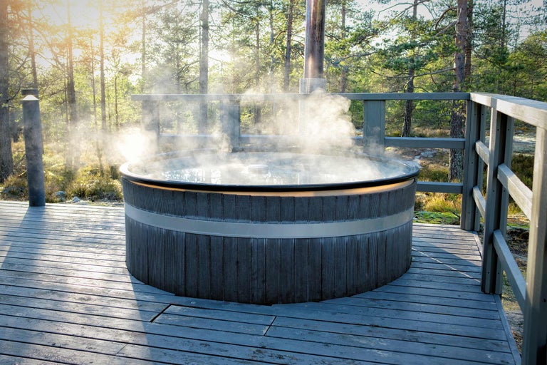 Holzbeheizter Badezuber mit dampfendem Wasser im Außenbereich