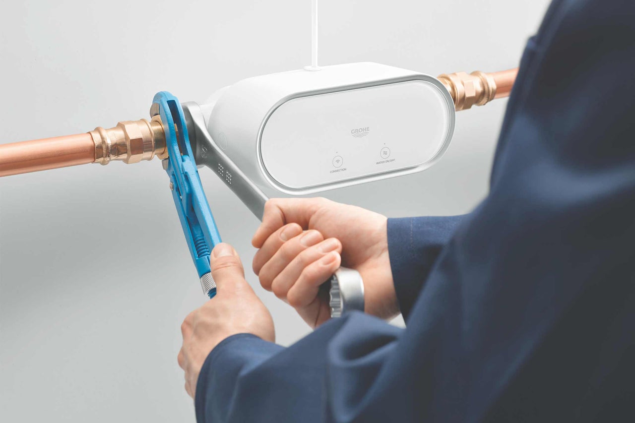 Installation des Grohe Sense Guard Wassersensors an einer Wasserleitung mit einem Schraubenschlüssel.