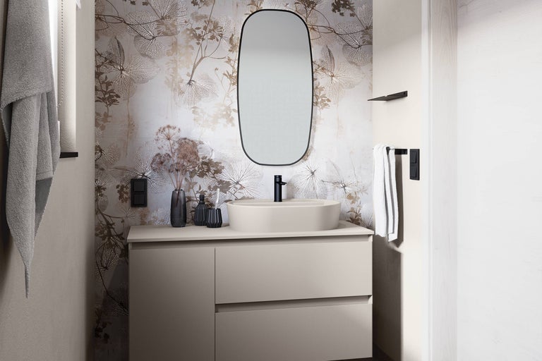Helles Badezimmer mit Waschtisch, Spiegel, Armatur und floraler Tapete