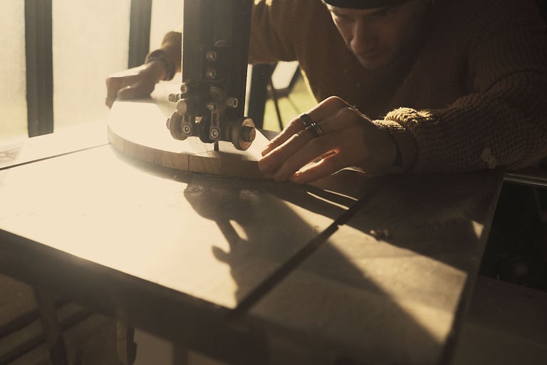 Handwerker bei der Arbeit mit einer Bandsäge an einem Holzstück.
