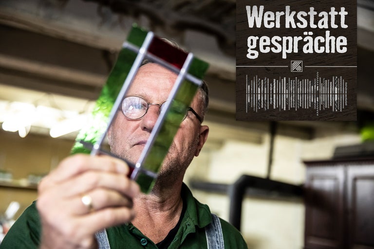 Mann betrachtet farbiges Glasstück; Werkstattgespräche