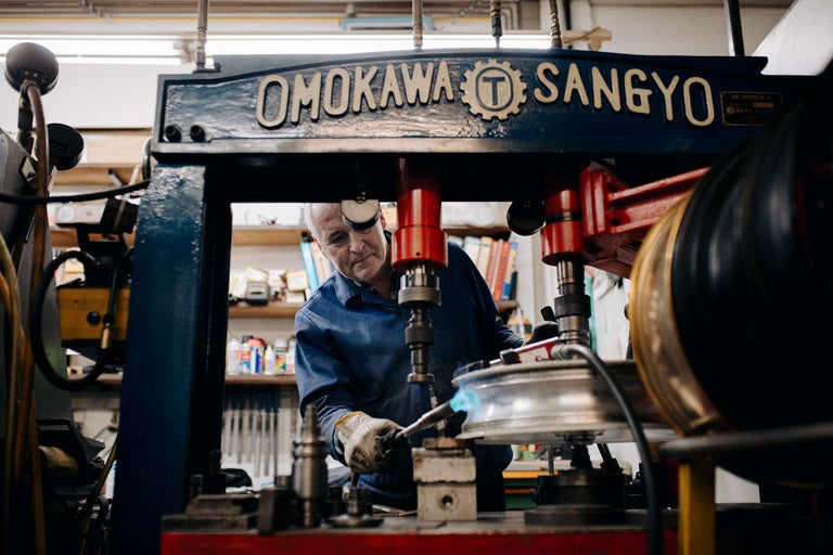 Ein Mann arbeitet mit einer Schweißmaschine an einem Metallobjekt in einer Werkstatt.