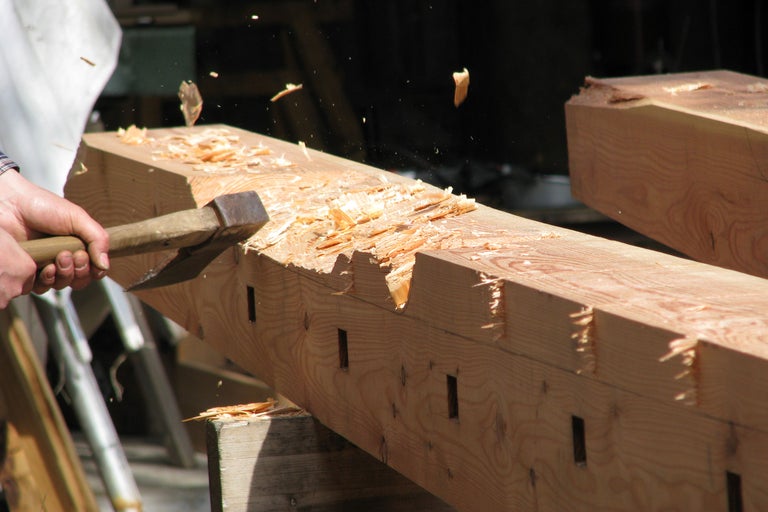Holzbearbeitung mit Axt an einem Holzbalken