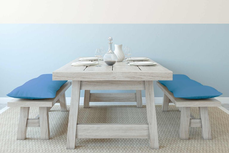 Esstischgarnitur aus Holz mit Bänken und blauen Kissen auf einem Teppich