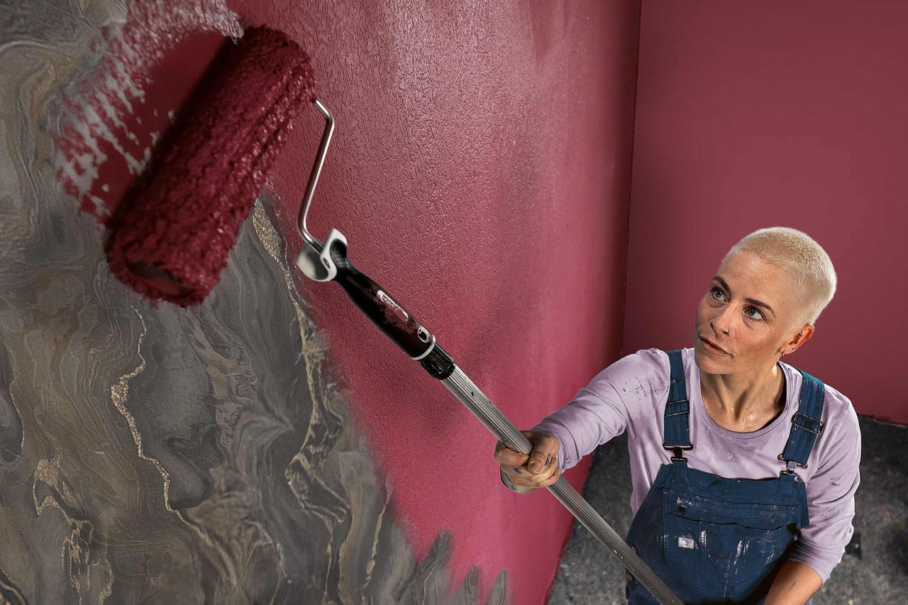 Eine Person streicht eine Wand mit einer Farbrolle.