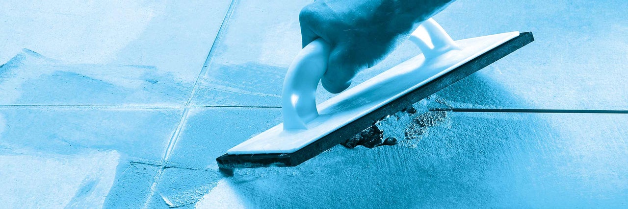 Hand mit Fugengummi beim Verfugen von Fliesen