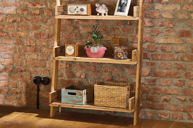 Holzregal mit Dekorationselementen vor einer Ziegelwand