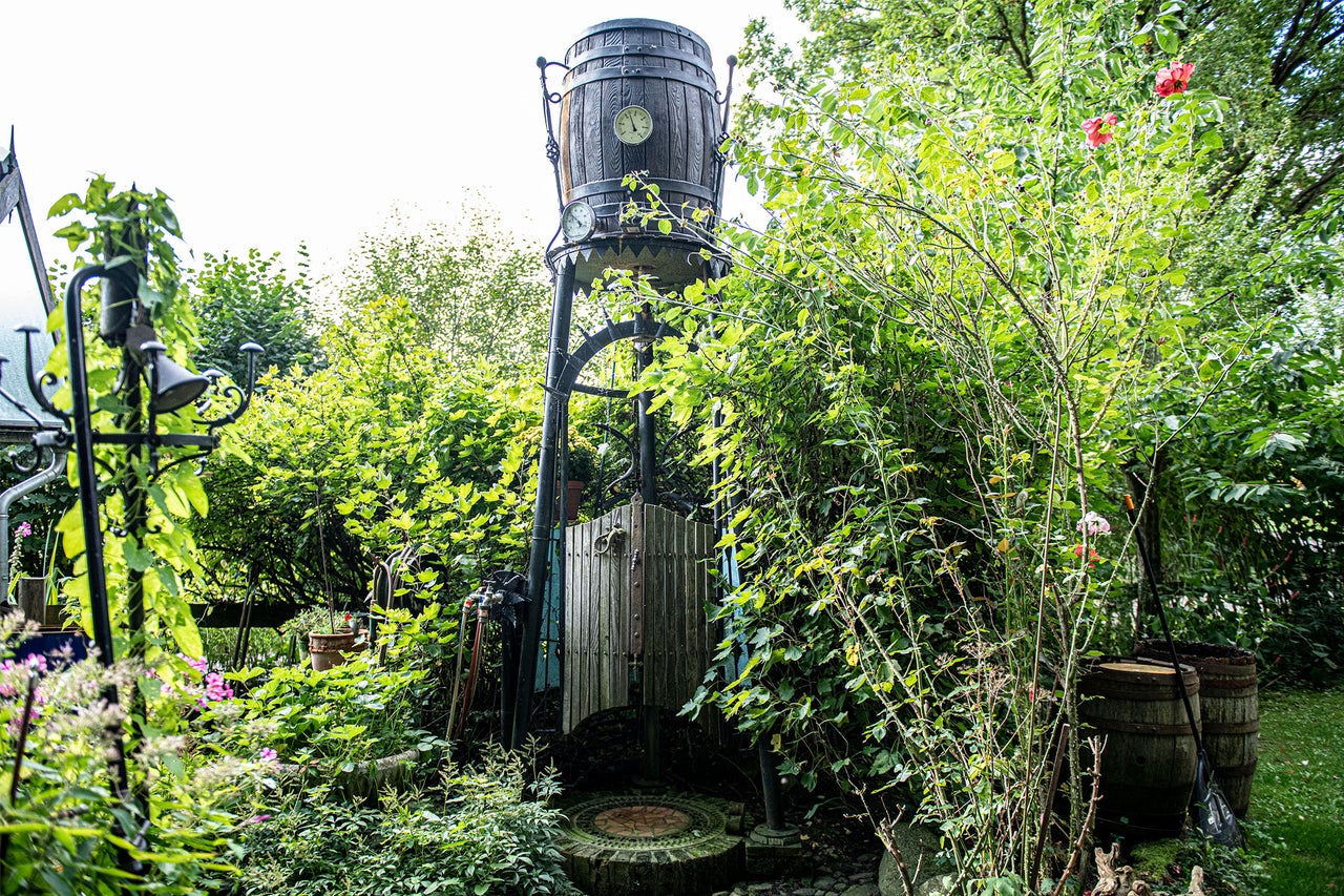 Gartenansicht mit dekorativer Fassdusche und üppiger Bepflanzung