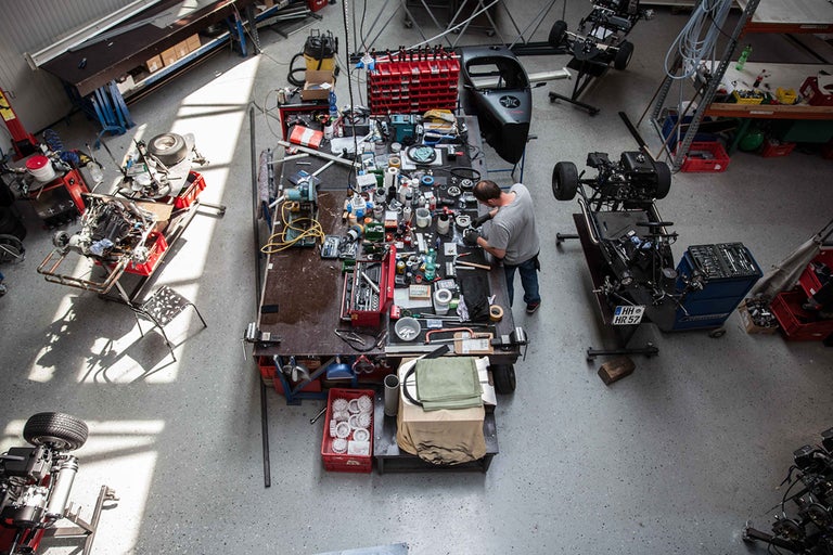Übersicht eines Werkstattbereichs mit Werkzeugen, Maschinen und einem Mechaniker