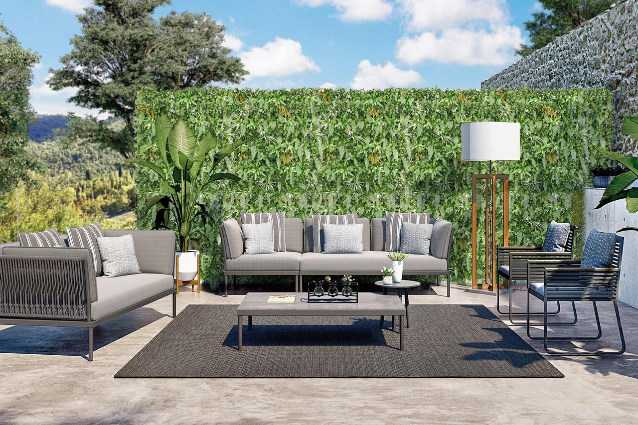 Terrasse mit Sofa, Sesseln, Tisch, Teppich und Pflanzenwand