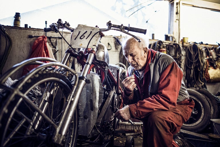 Ein Mann repariert in einer Werkstatt ein Motorrad.