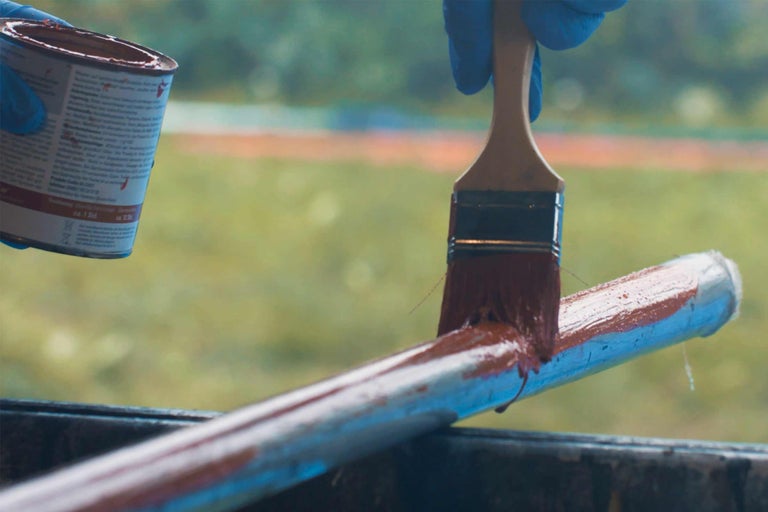 Farbe wird mit einem Pinsel auf ein Rohr aufgetragen.