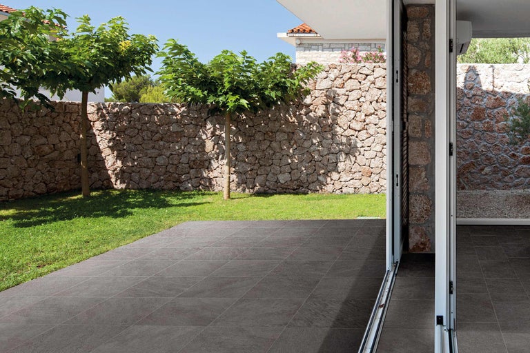 Terrasse mit Steinmauer, Bäumen und Bodenfliesen