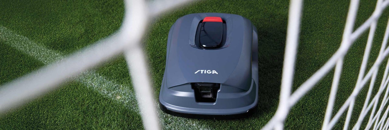 Grauer Stiga Mähroboter auf Rasen neben Fußballnetz