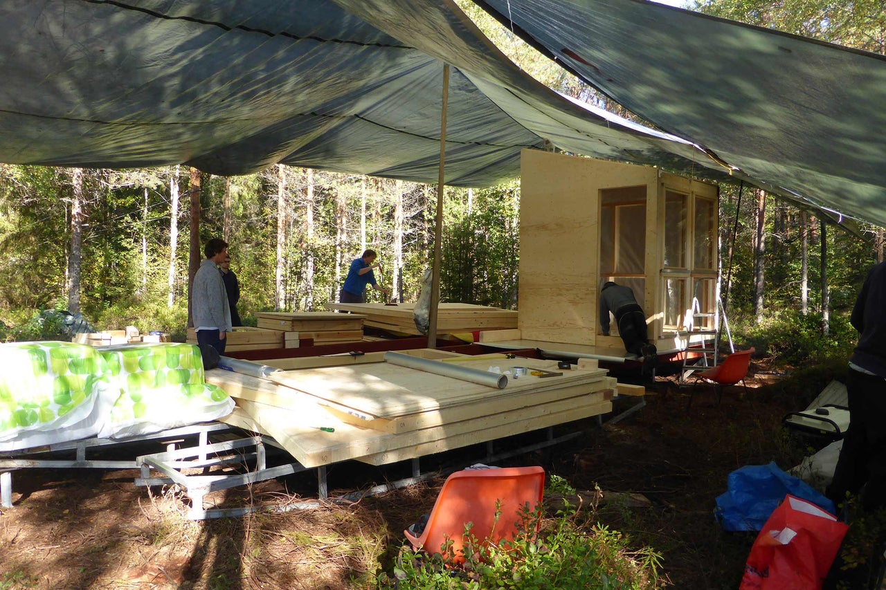 Bau einer Holzhütte im Wald mit Holzplatten und Planen