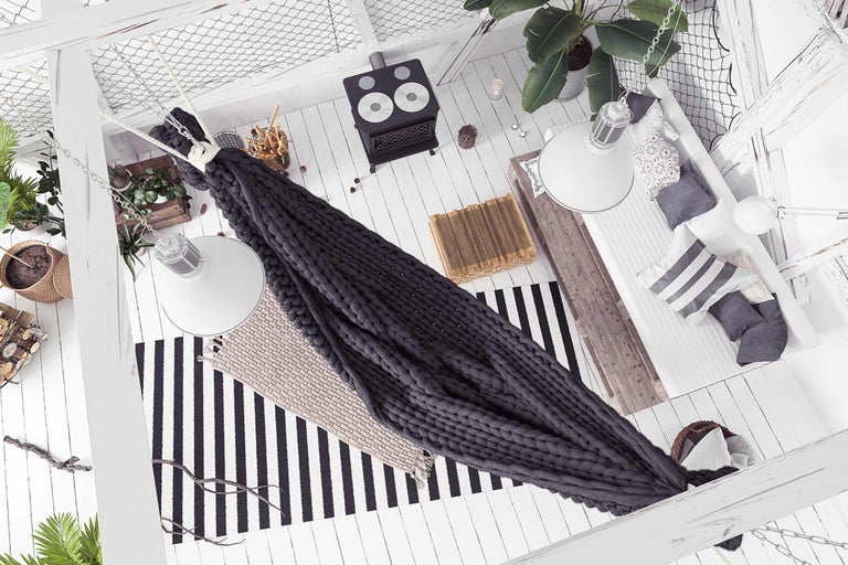 Innenraumansicht mit Hängesessel, Kaminofen, Teppichen, Pflanzen und Dekorationen.