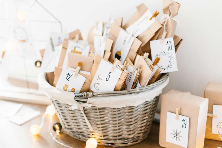 Gefüllter Adventskalender mit nummerierten Päckchen in einem Weidenkorb.