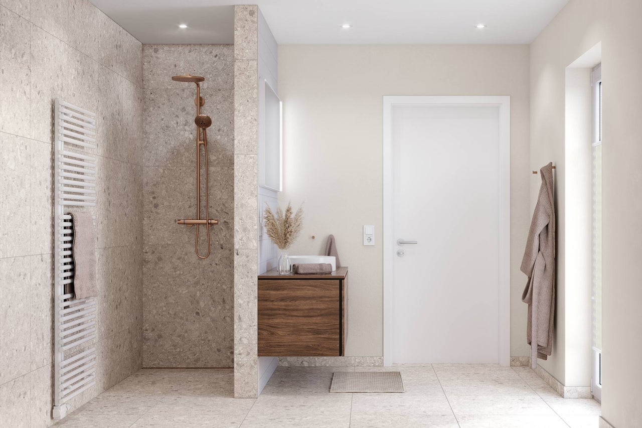 Modernes Badezimmer mit begehbarer Dusche, Terrazzo-Fliesen, kupferfarbenen Armaturen und einem Waschtischunterschrank in Holzoptik.