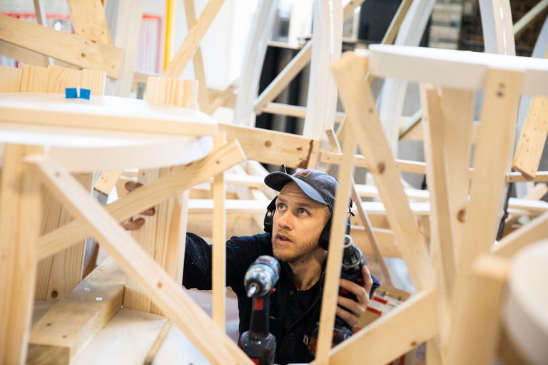 Mann montiert Holzkonstruktion mit Akkubohrer