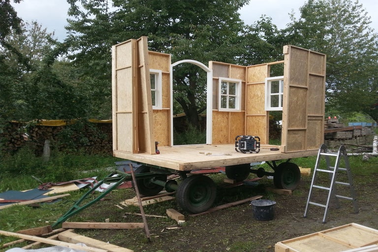 Bauwagen im Rohbau mit Holzrahmen und Fenstern auf einem Anhänger