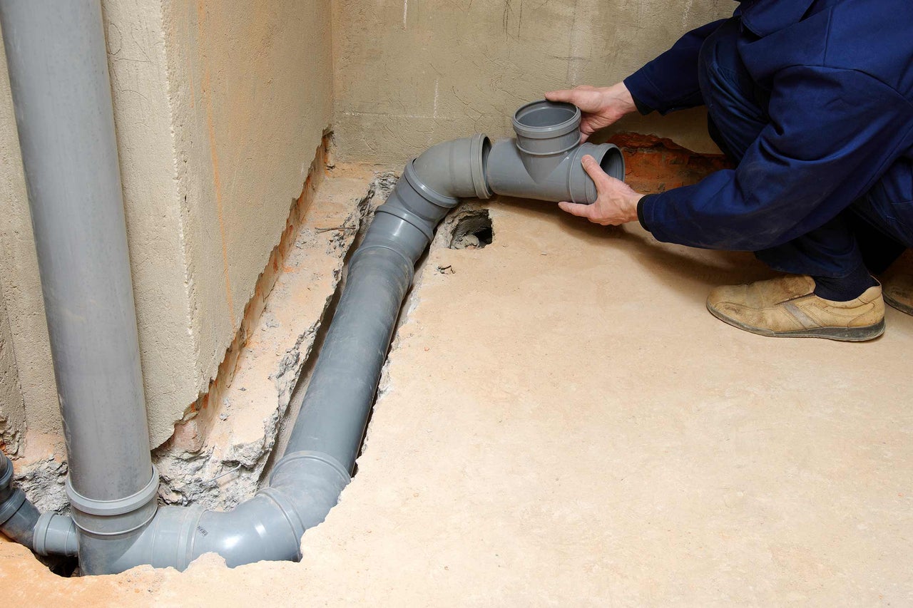 Installation von grauen Abwasserrohren im Keller durch einen Installateur