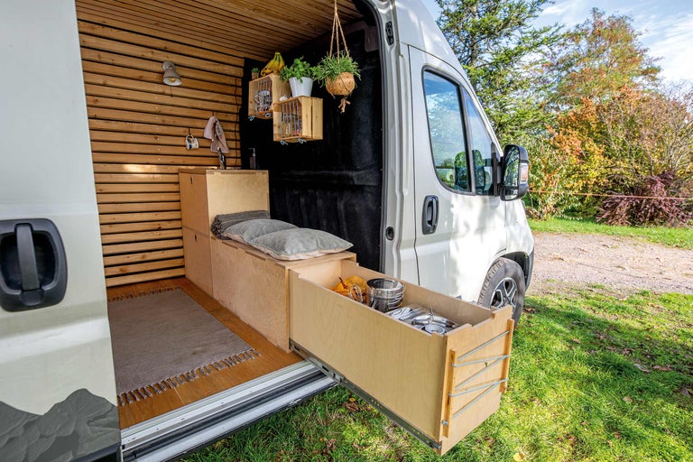 Innenraum eines Lieferwagens mit Holzausstattung, Stauraummöbeln und ausziehbarer Schublade