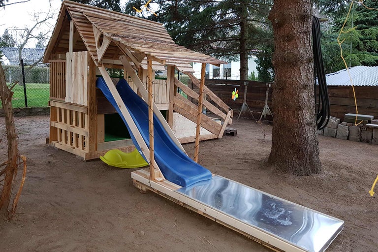 Spielplatz mit Rutsche aus Holz im Außenbereich