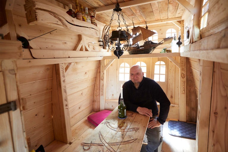Holzspielhaus im maritimen Stil mit Mann am Tisch