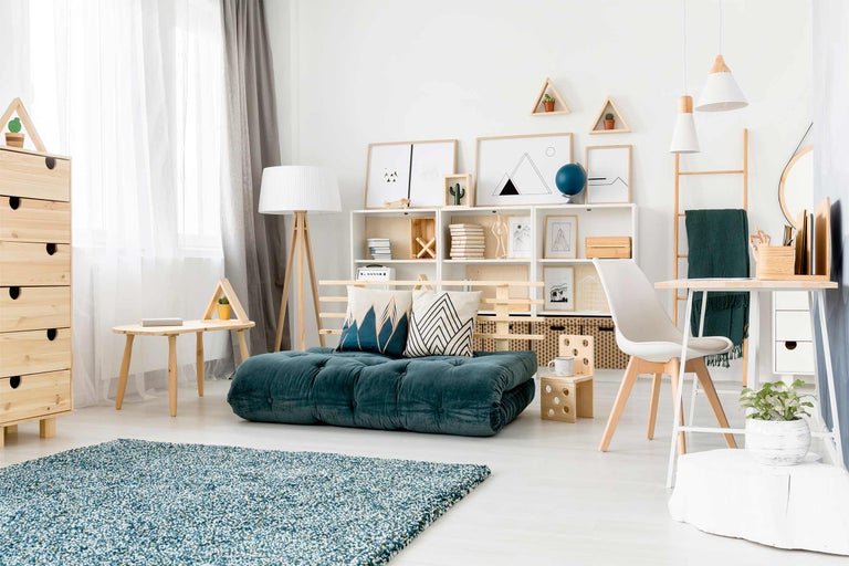 Heller Wohnraum mit blaugrüner Matratze, Regalen und Holzelementen