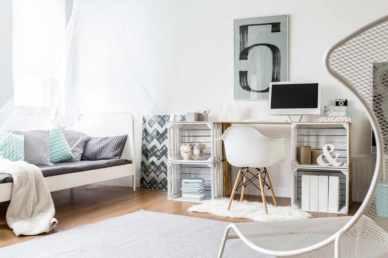 Helles Zimmer mit Bett, Schreibtisch aus Holzkisten, Stuhl und Teppich