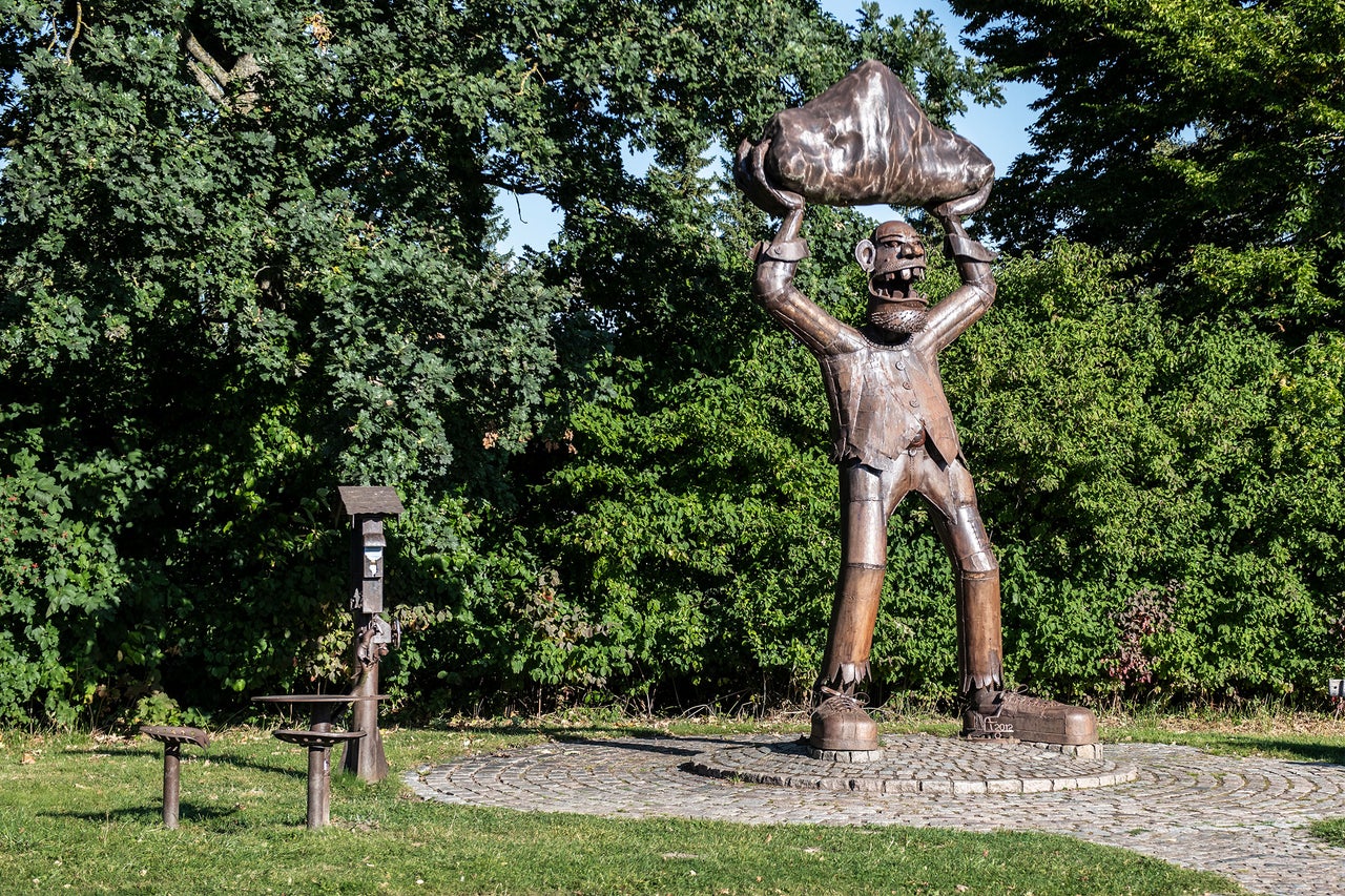 Skulptur einer Figur, die einen Felsen über dem Kopf hält